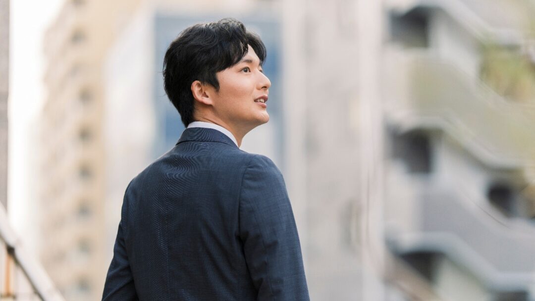 オフィス街にて遠くを眺める30代若手コンサルタント