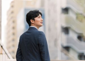 オフィス街にて遠くを眺める30代若手コンサルタント